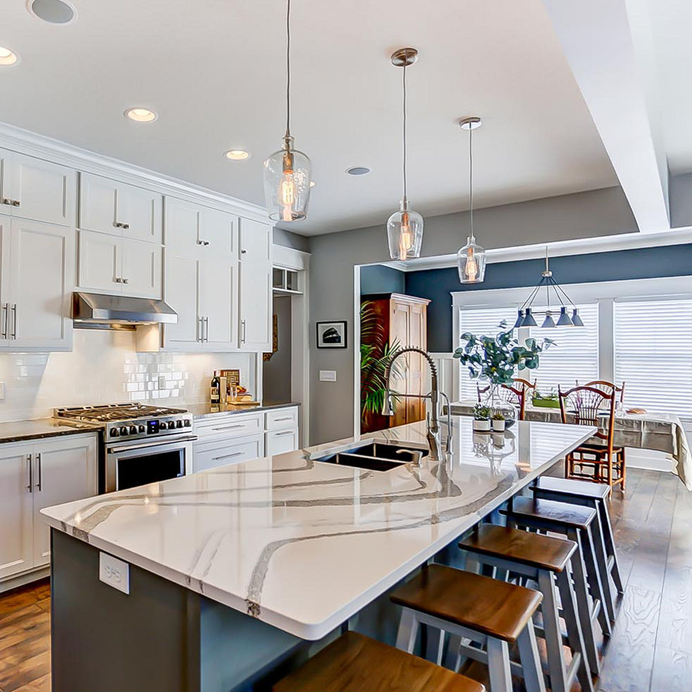 Side view of a kitchen and island area with Cambria Minera countertops around the stove and Cambria Annicca countertops on the island