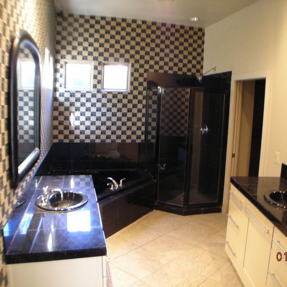 Bathroom with brown tiling, a black bathtub, shower, and countertop.