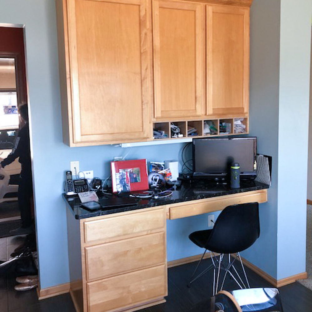 A work space with a black computer monitor, telephone and an office chair.
