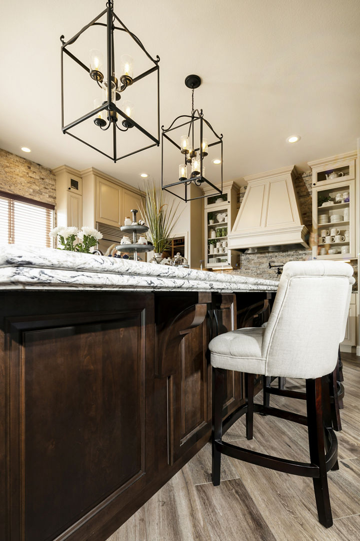 a island made from dark wood, topped with quartz countertops and a traditional countertop edge profile, with white barstools and pendant lighting.