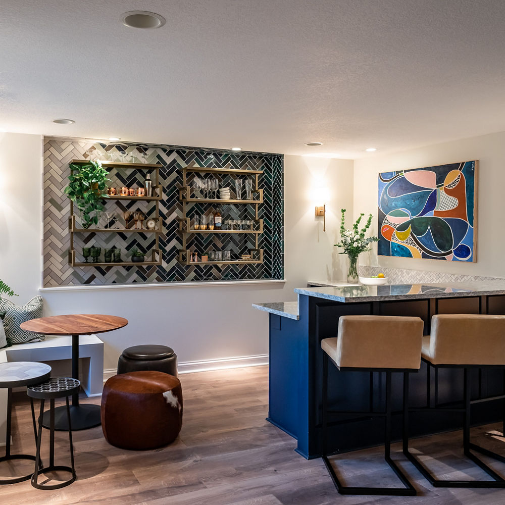 a basement bar with blue cabinets, gray quartz countertop bartop, a fun built-in shelf, and lots of seating. 