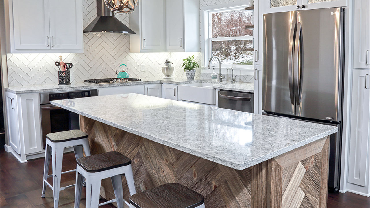 A farmhouse kitchen with a counter and island featuring Cambria Berwyn quartz countertops.