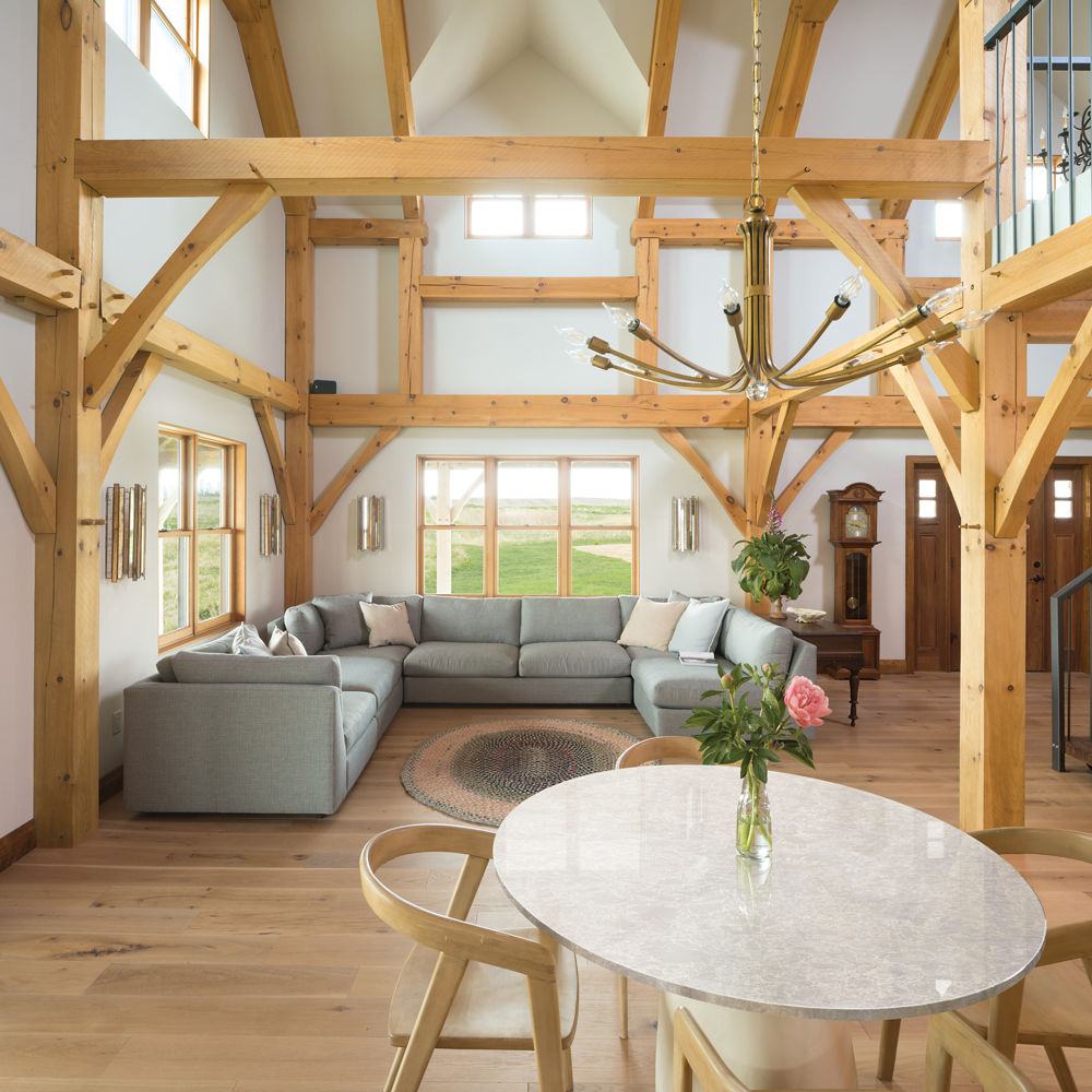 A lodge inspired living and dining room with open beams, a large sectional couch, and a quartz dining table.
