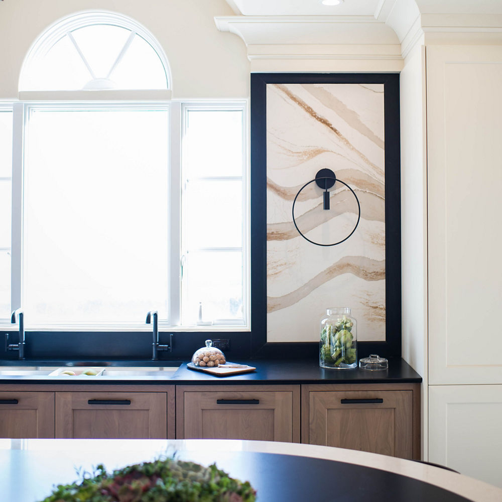 A contemporary kitchen with an island featuring Cambria Brittanicca Gold Warm quartz countertop and wall panels with Cambria Blackpool Matte quartz.