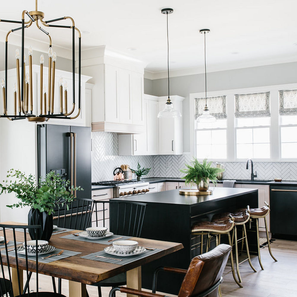 a black and white kitchen with white cabinets, a black island, black appliances and black quartz countertops.