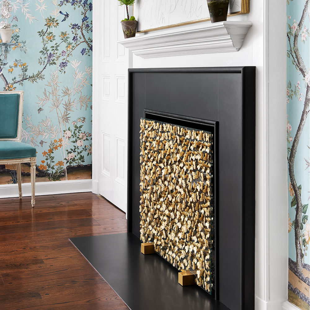a fire place made from black quartz in a living room with blue floral wallpaper. 