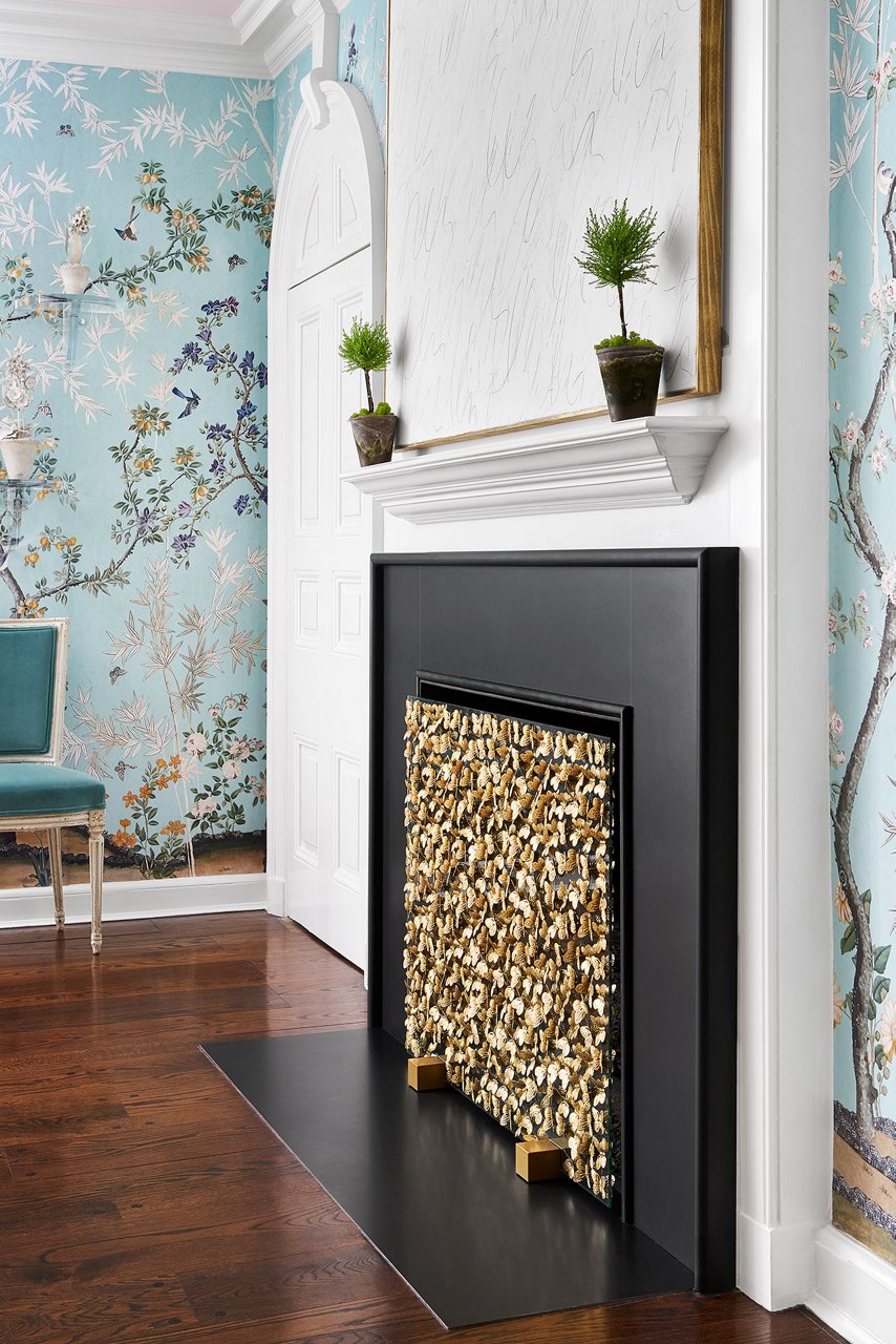 a fire place made from black quartz in a living room with blue floral wallpaper. 