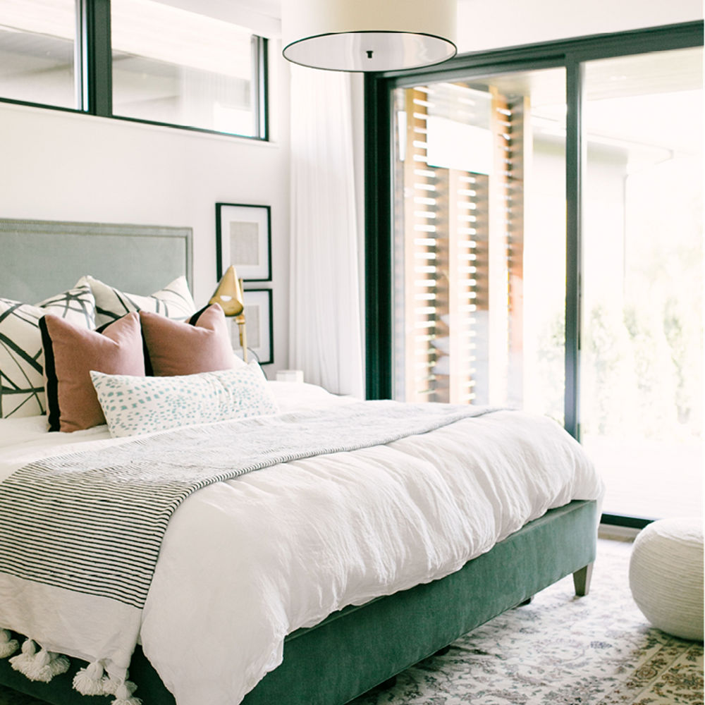 A bedroom featuring a green, white, and brown palette with a nearby window and sliding door.