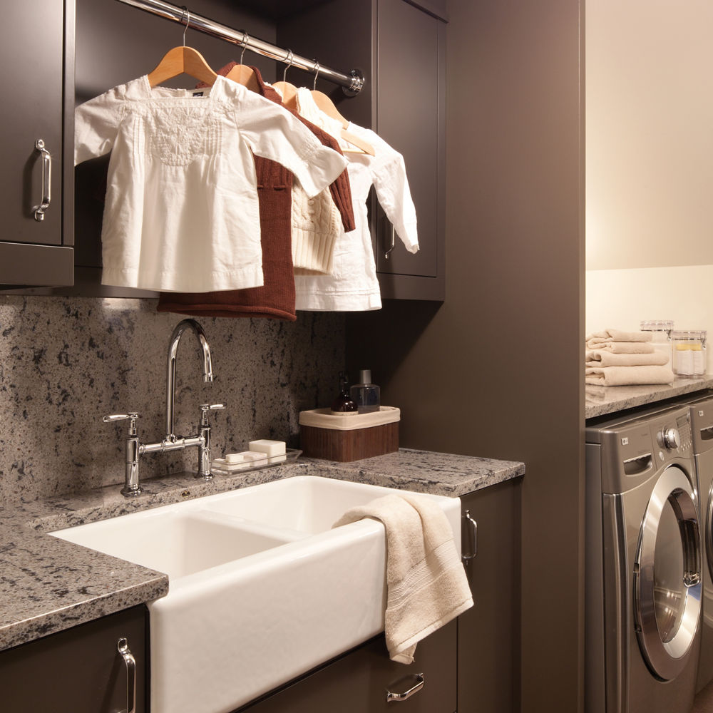 a laundry room with dark brown cabinets, a large utility sink, gray quartz countertops to provide a granite alternative, and hanging storage for drying clothes. 