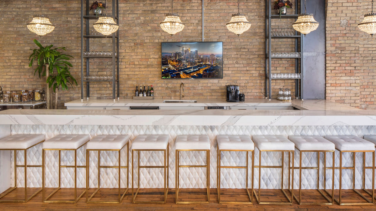 A long table with ten stools in front of it with a Cambria Brittanicca quartz waterfall edge.