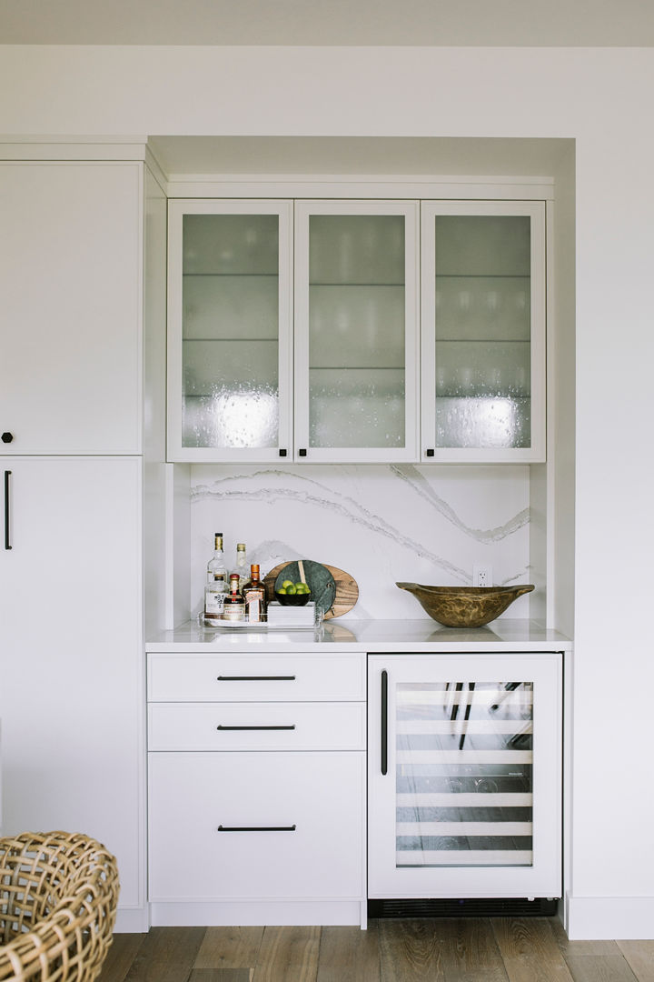 a dry bar white white and gray veined quartz countertops and matching backsplash, white cabinets, a white mini fridge, and frosted glass upper cabinets. 