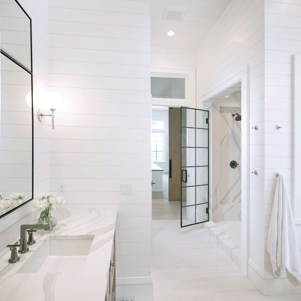 A stunning bathroom with a vanity topped with white quartz countertops and a luxurious walk-in shower made from the same quartz design.