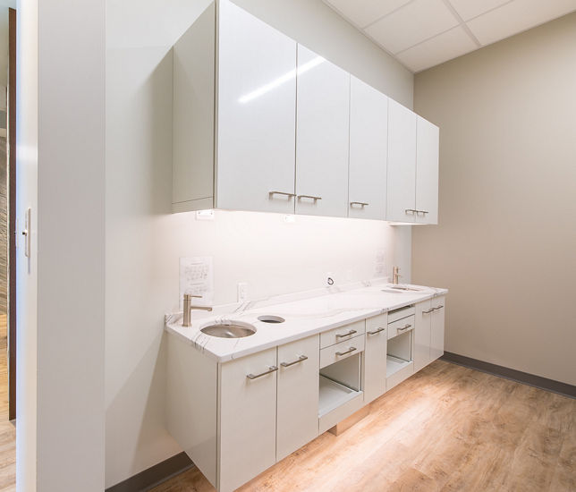Dental office area with white cabinets, gray walls, and two sinks, topped with Brittanicca quartz countertops.