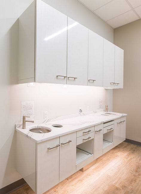 Dental office area with whit cabinets, gray walls, and two sinks, topped with Brittanicca quartz countertops.