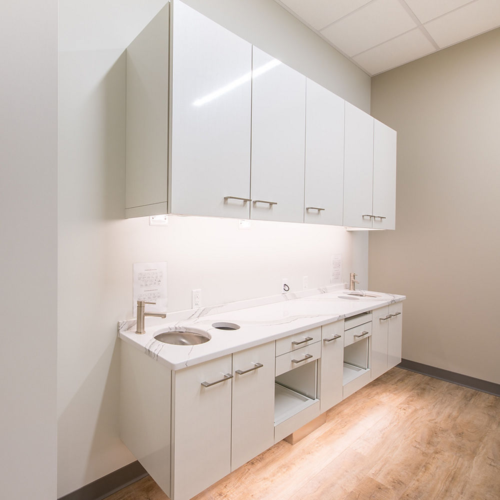 Dental office area with white cabinets, gray walls, and two sinks, topped with Brittanicca quartz countertops.