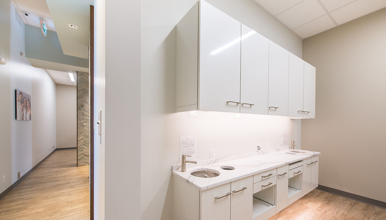 Dental office area with white cabinets, gray walls, and two sinks, topped with Brittanicca quartz countertops.