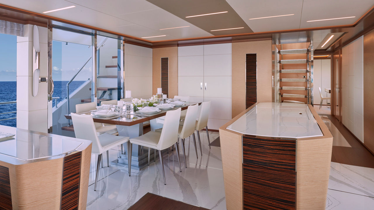 A kitchen inside of a yacht interior featuring a dining room and bar.