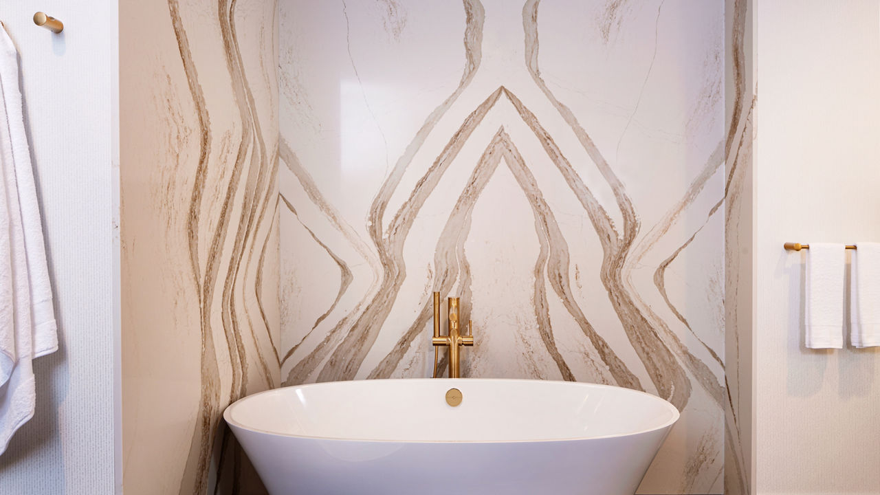 A bathroom with a large bathtub and a Brittanicca Gold Warm quartz wall