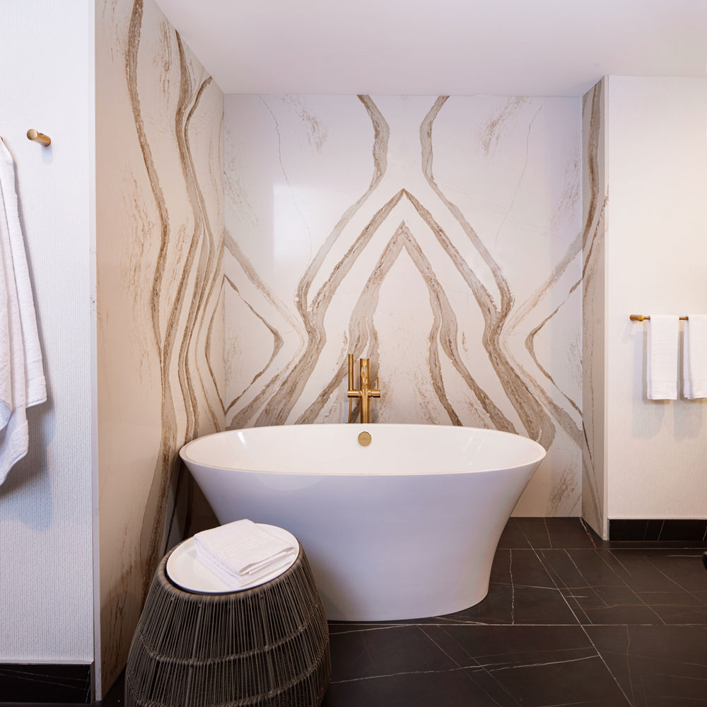 A bathroom with a large bathtub and a Brittanicca Gold Warm quartz wall