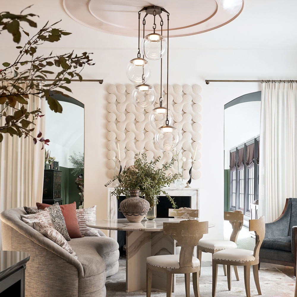 a gorgeous lounge area with a white quartz fireplace and matching table with warm white artwork, curtains, and furniture.