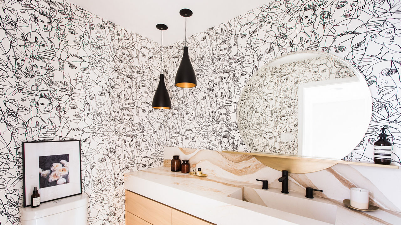 A bathroom with abstract wallpaper and a round circle mirror with a Brittanicca Gold Warm quartz vanity