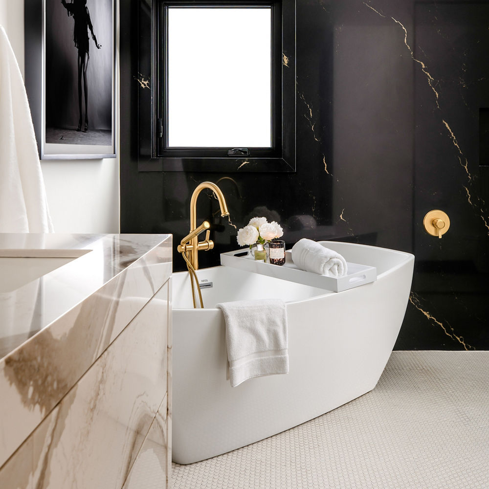 Bathroom with white bathtub and a Brittanicca quartz vanity and a Woodcroft quartz wall