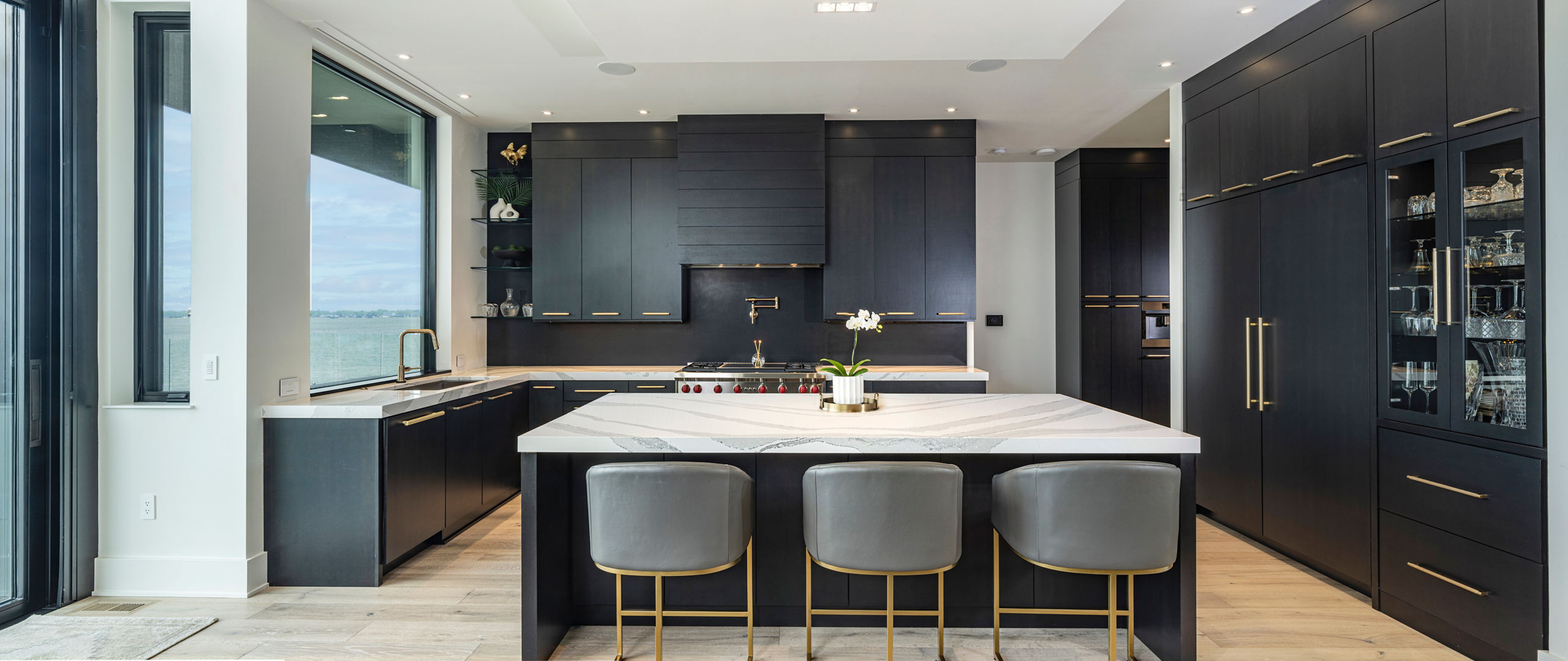 A large, dark wood kitchen with a large window and Brittanicca quartz countertops 