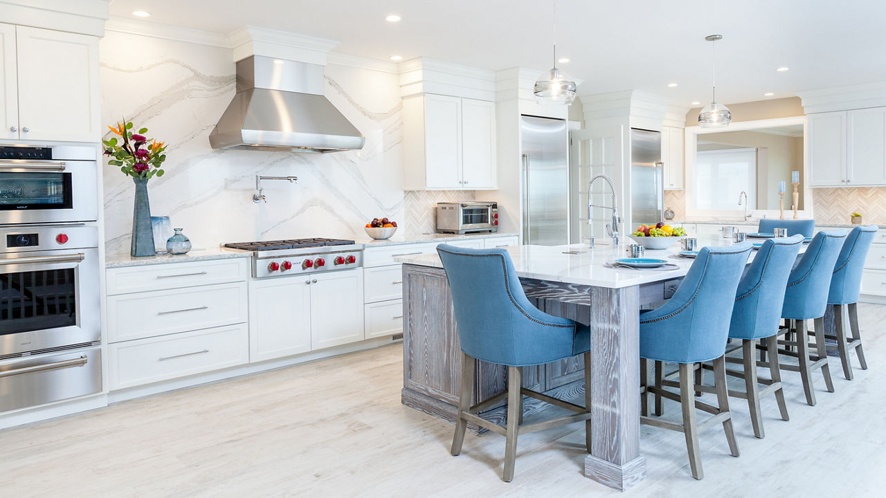 A white and blue kitchen with a Cambria Brittanicca quartz backsplash and countertop.