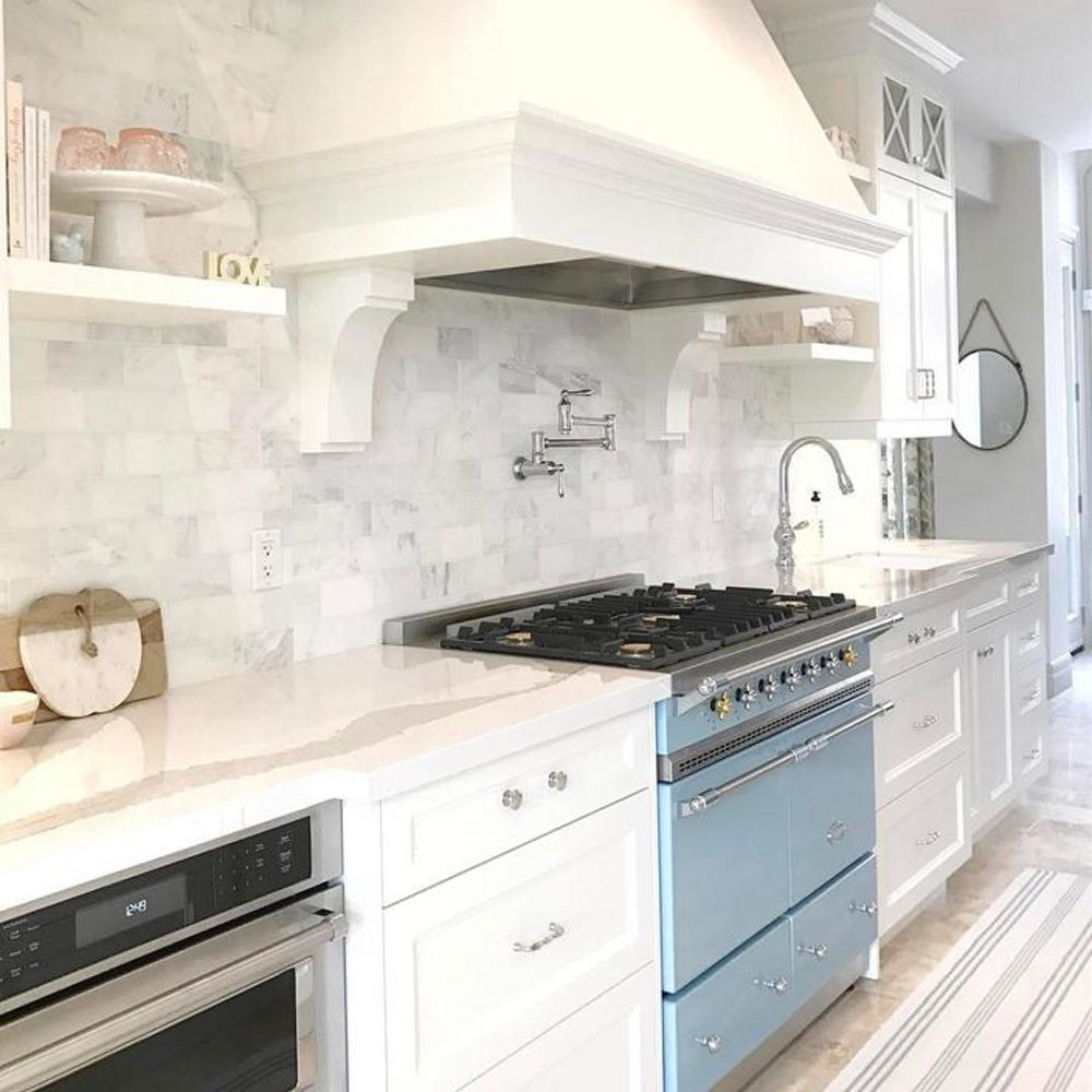 White kitchen with Brittanicca countertops and light blue range.