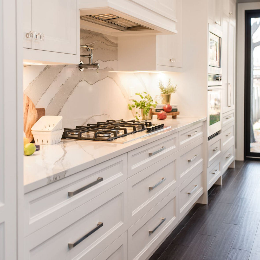 Kitchen with white cabinets featuring a stove atop Cambria Brittanica quartz countertops.