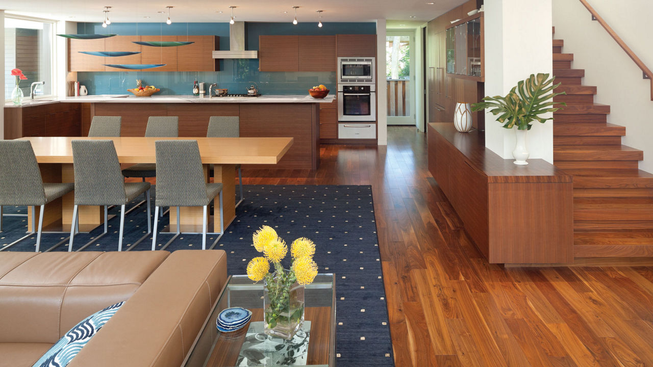 An open-concept layout with a kitchen in the back featuring white quartz countertops, a wooden dining table, and a living room.