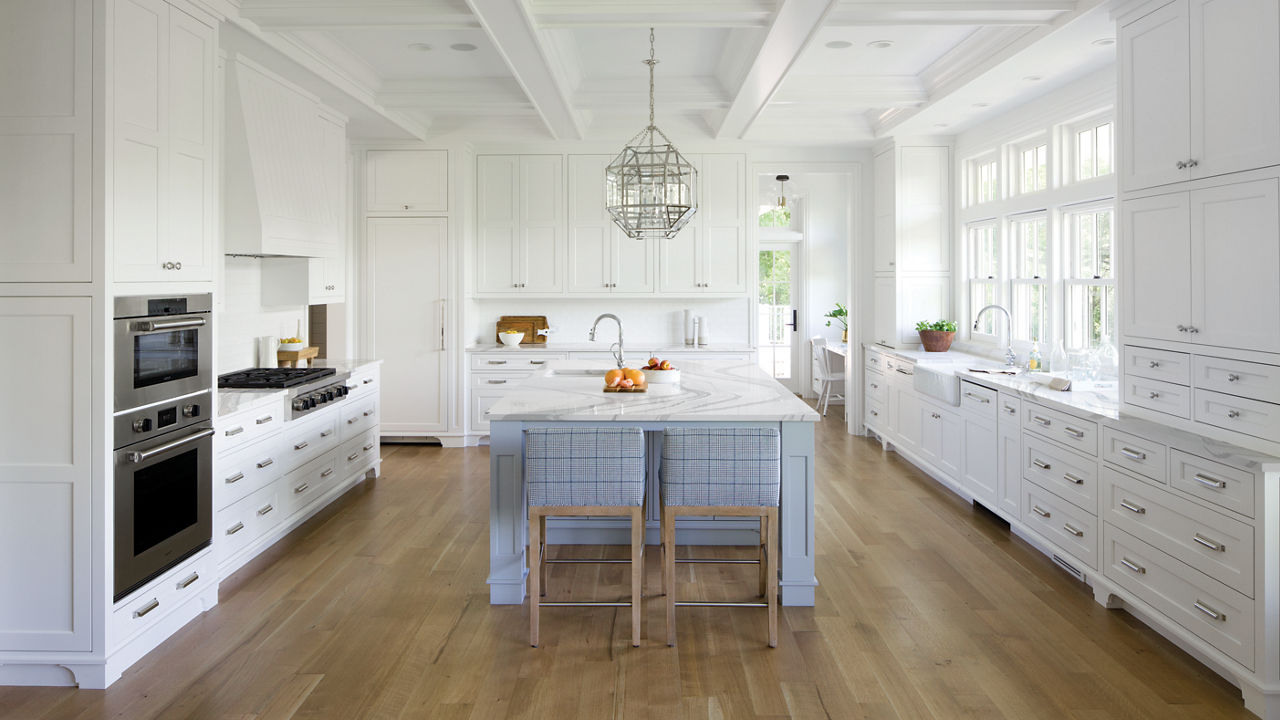 White kitchen with light blue-gray island and Brittanicca countertops.