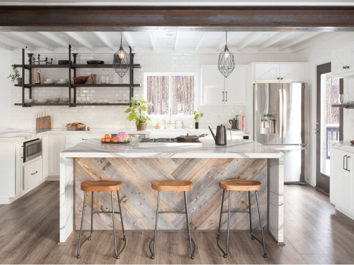 a modern farmhouse inspired kitchen with white cabinets, black open shelving, and a center island with wooden pattern backdrop and white quartz double waterfall edge countertops