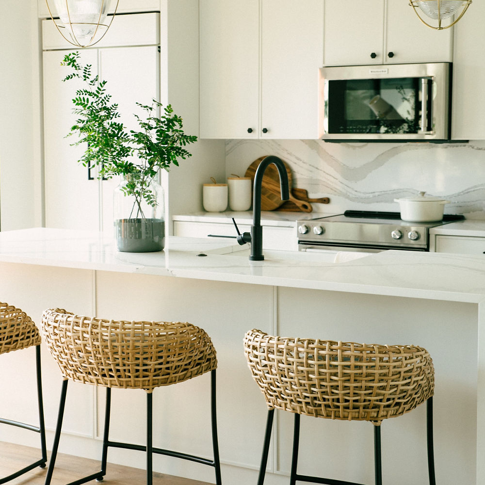 Two wooden stools in front of a kitchen island with a Cambria White Brittanicca quartz countertop.