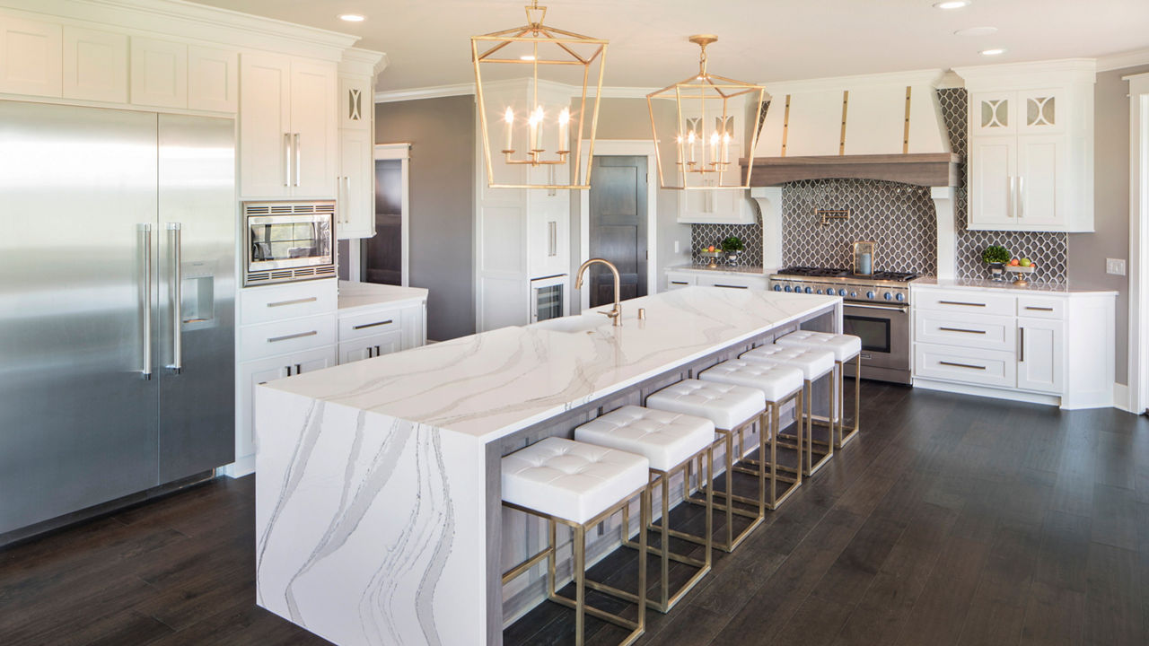 A gorgeous white kitchen with a double waterfall island topped with Cambria Brittanicca quartz countertops.