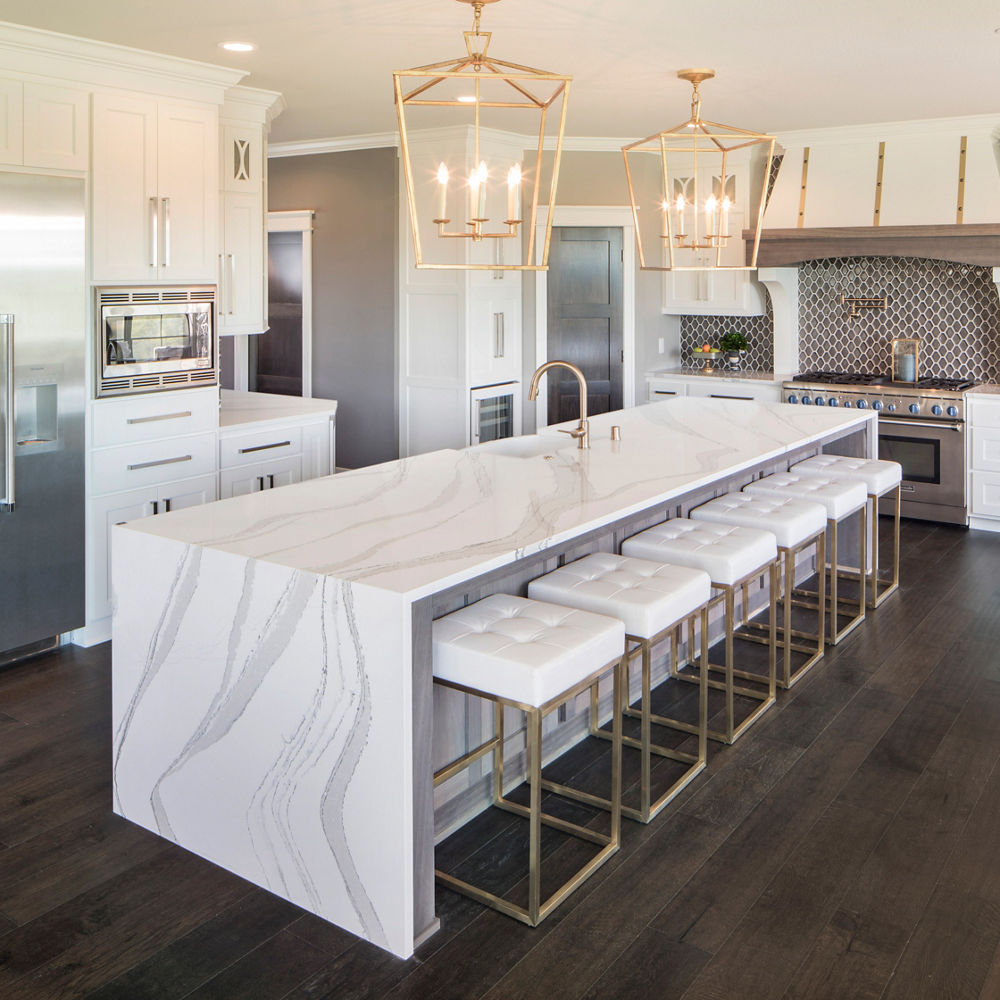 A gorgeous white kitchen with a double waterfall island topped with Cambria Brittanicca quartz countertops.