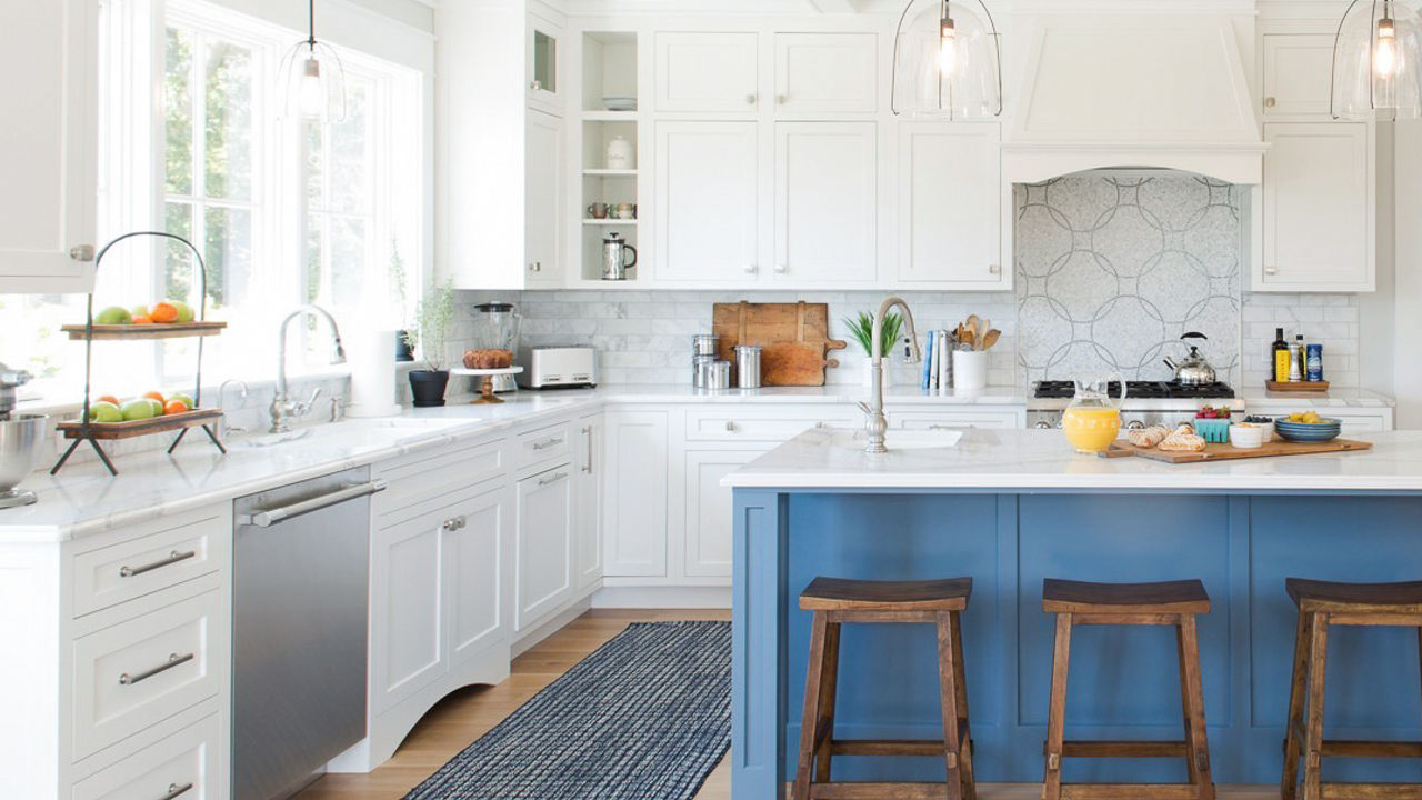 Kitchen with white cabinets and blue island. The counter and island feature Cambria Brittanicca quartz countertops.
