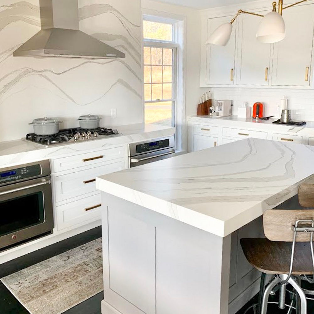 A kitchen with a counter and island featuring Cambria surfaces.