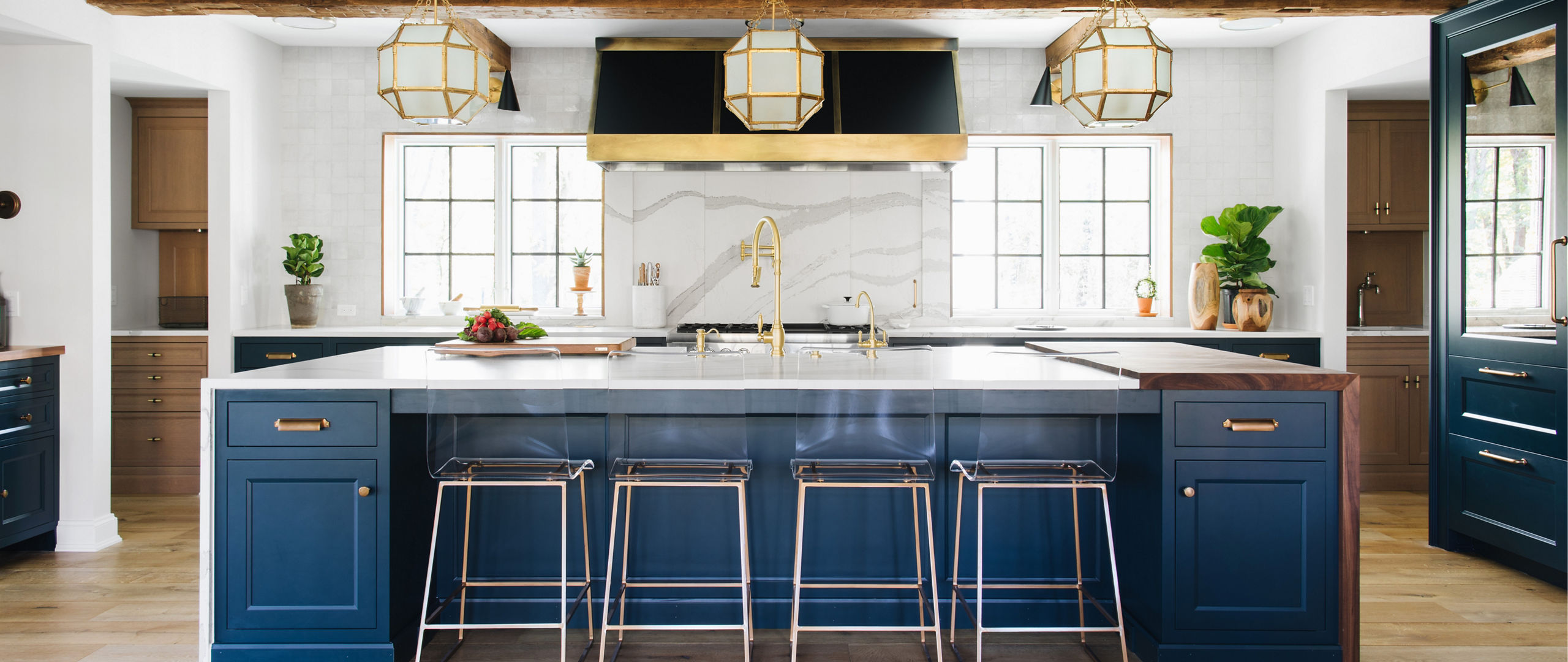 Photograph of a kitchen with a large island with navy blue sides and cupboards and a gray matte countertop.