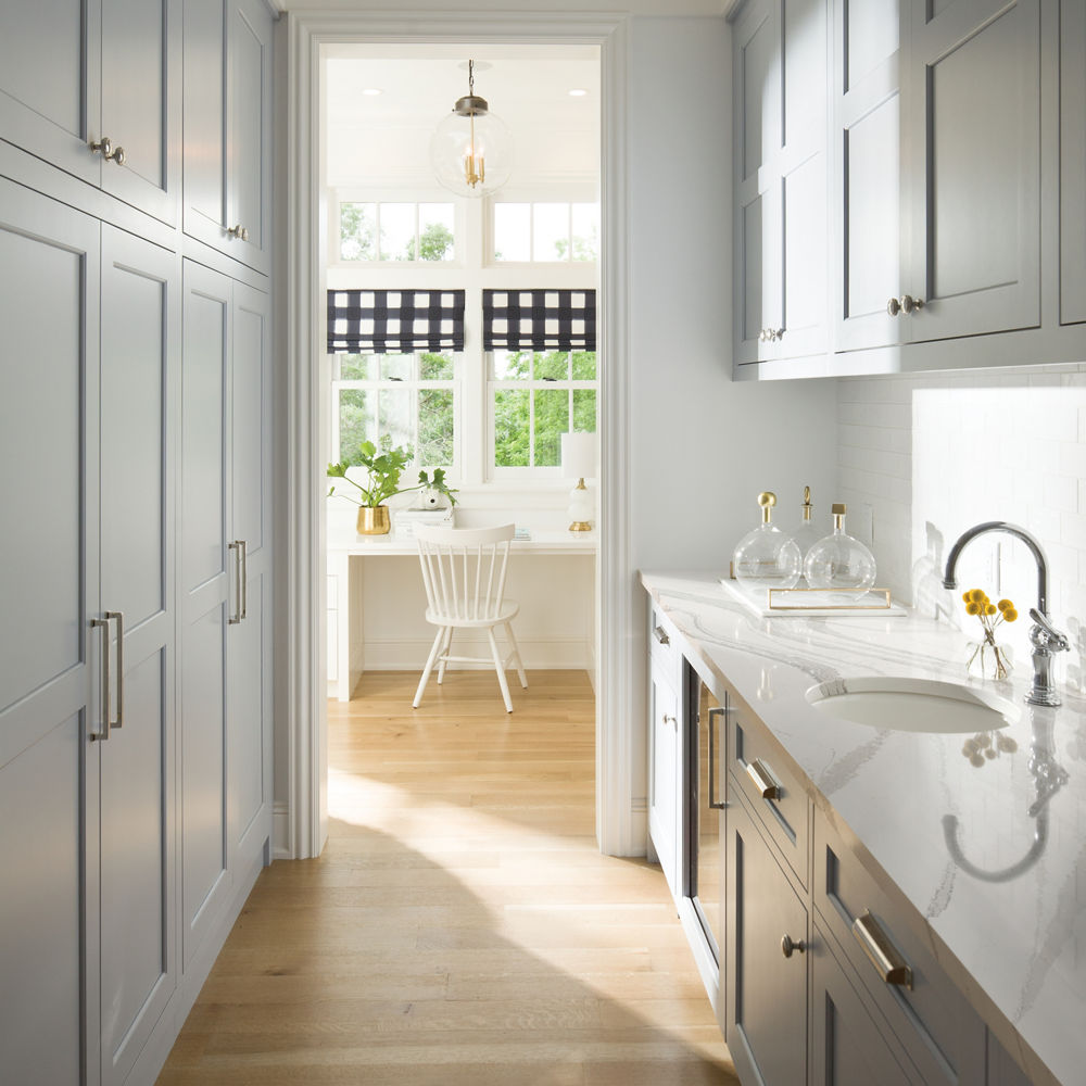 A coastal inspired butler pantry with light blue cabinets and white quartz countertops.