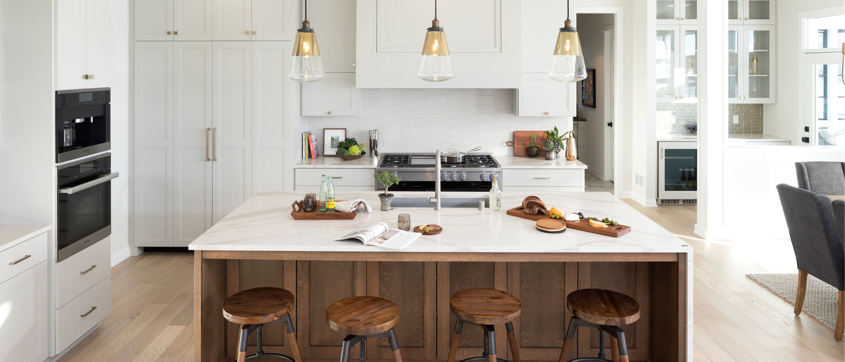 A warm kitchen with a counter and island featuring Cambria Brittanicca Warm quartz countertops.