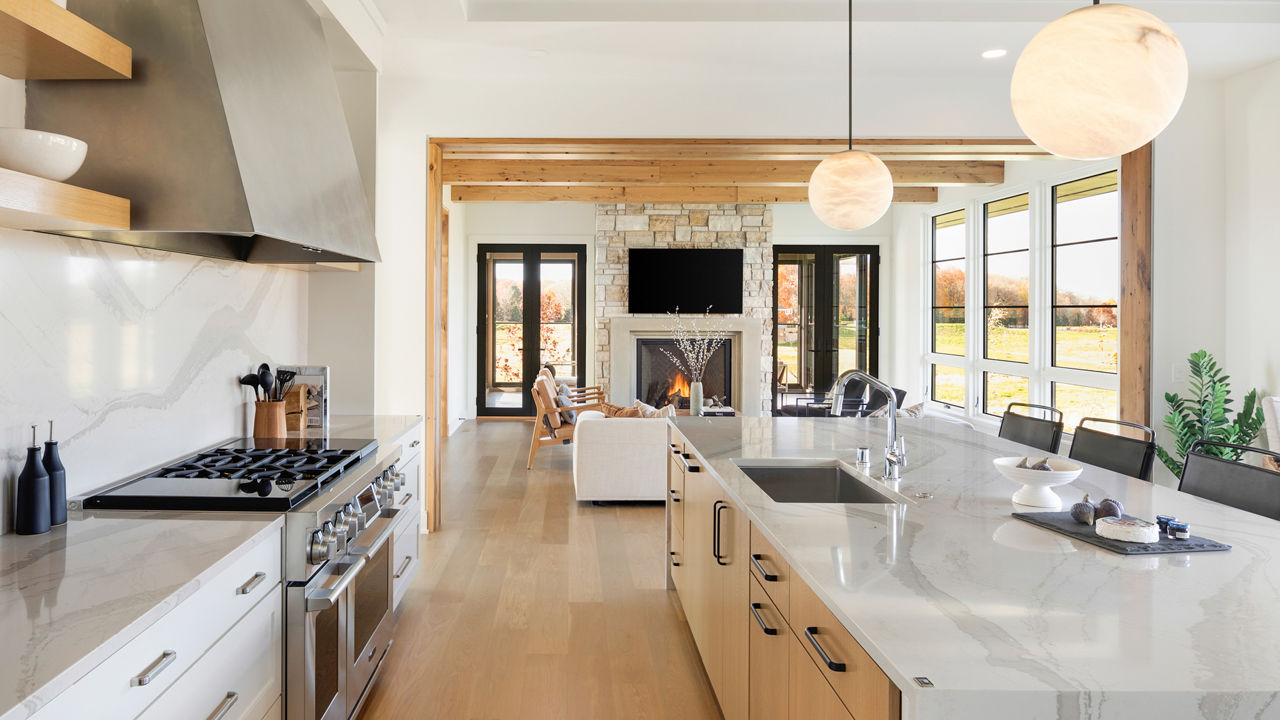 White kitchen with wood floor and cabinets featuring Brittanicca Warm quartz countertops.