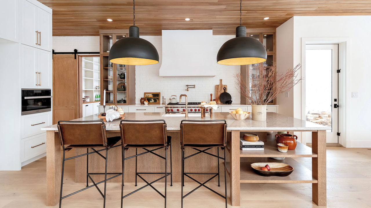 a warm and inviting kitchen with wooden ceilings and flooring, white cabinets, white quartz countertops, and black and gold accents.