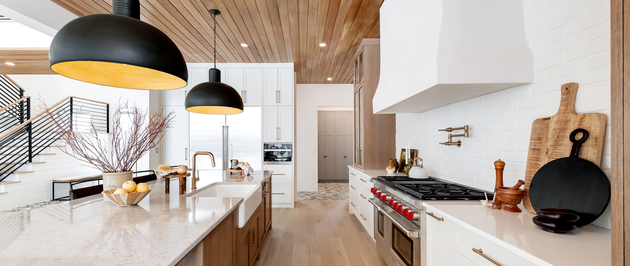 a gorgeous kitchen with white cabinets, white quartz countertops, and a large island with a farmhouse sink.