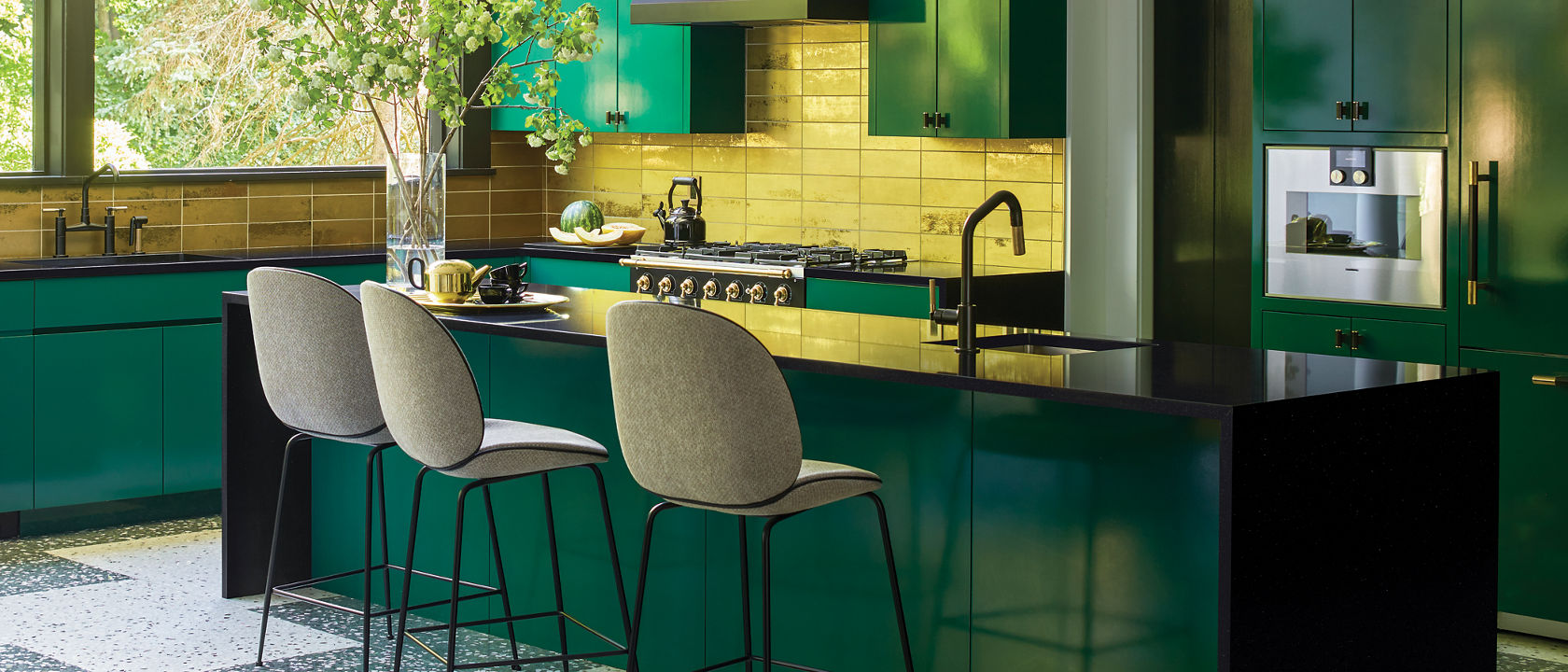 Designer : A. Villalobos 
Instagram: @avillalobosdesign
â ¢Kitchen cabinets are painted in â  Chrome Greenâ   by Benjamin Moore in High gloss 
â ¢Countertop are Black Pool by Cambria 
â ¢Stove is by La Cornue 
â ¢Backsplash is Elenco Gold Tile by Ann Sacks
â ¢Light over counter is name â  Porteâ   by Urban Electric 
â ¢Flooring is custom terrazzo tiles by A. Villalobos through Concrete Collaborative 
â ¢Set of Plates over the stove are Portuguese Majolica through Christieâ  s 
â ¢Counter stool is The Beetle by Gubi