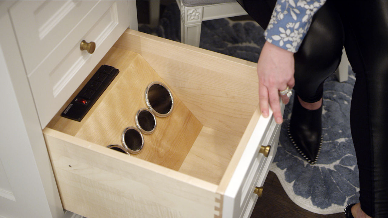 A custom vanity drawer with four outlets to hold hair appliances inside of the drawer.
