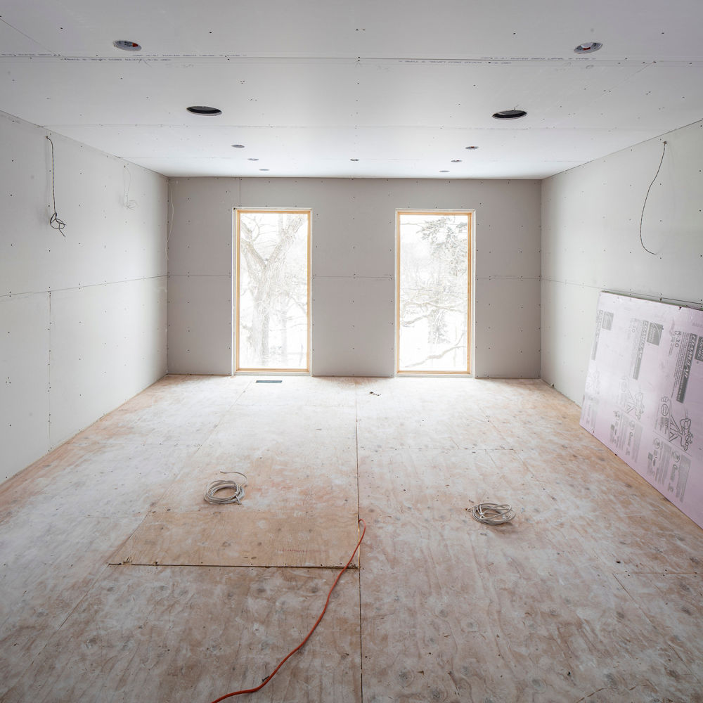 A closet under construction with two large windows illuminating the room with natural light.