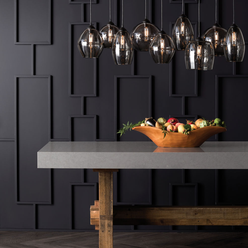 A dining table with a Cambria Carrick quartz countertop under a decorative chandelier.