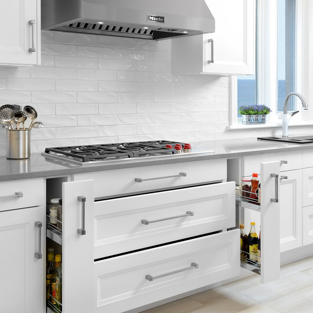 A kitchen featuring white narrow drawers and a utensil holder atop a Cambria Carrick quartz countertop.