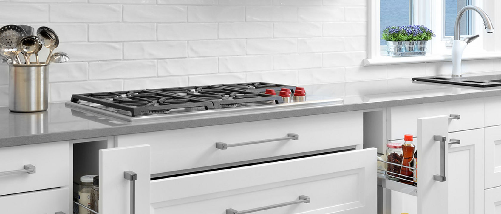 A kitchen featuring white narrow drawers and a utensil holder atop a Cambria Carrick quartz countertop.